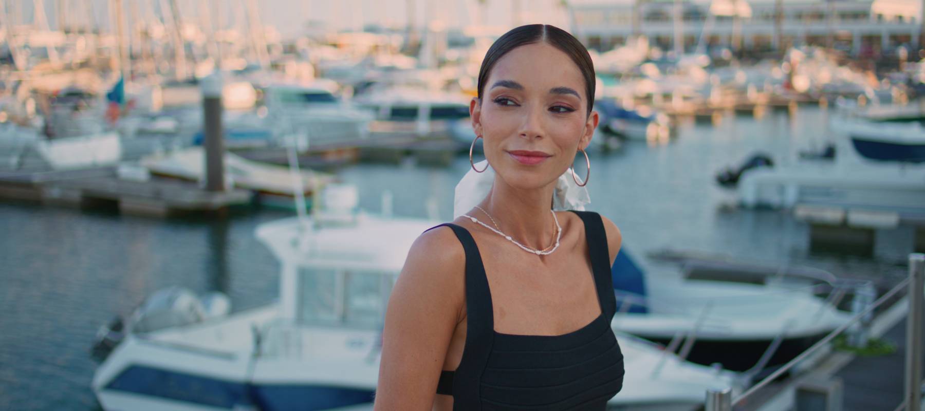 Stylish young woman looking sideways near yachts.