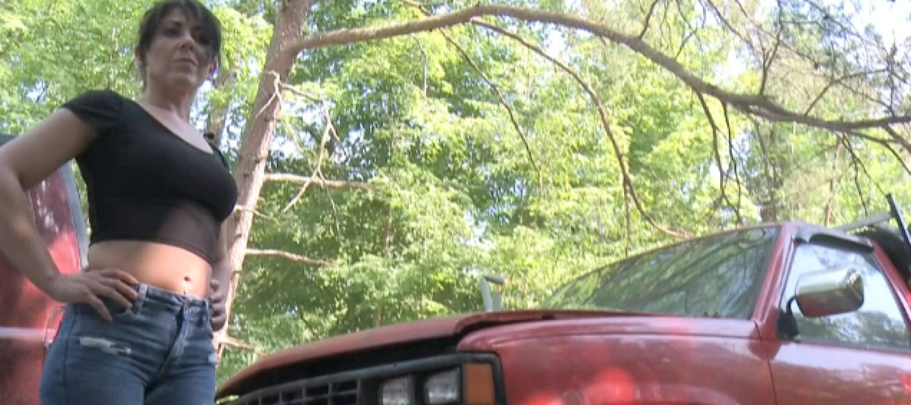 A woman stands next to a red truck.