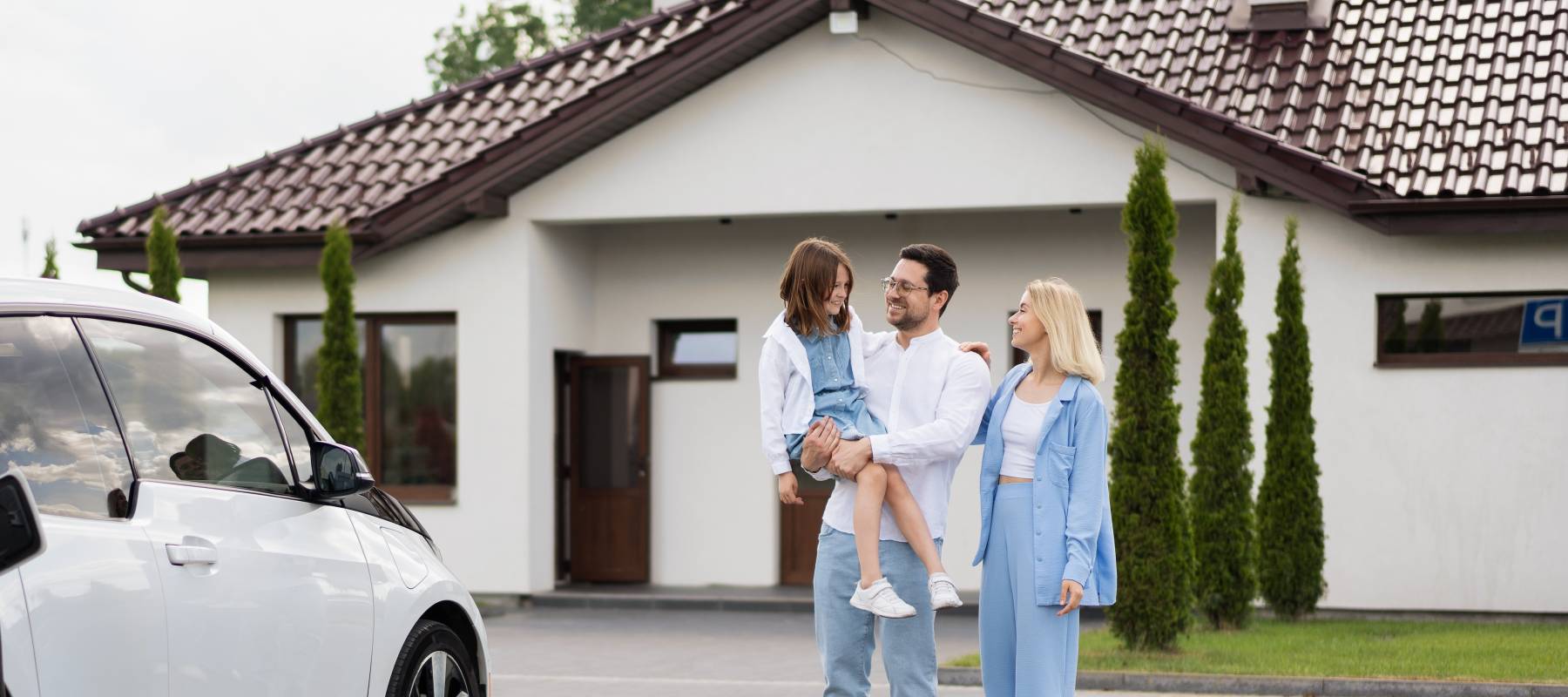 Affluent family in driveway in front of nice house.