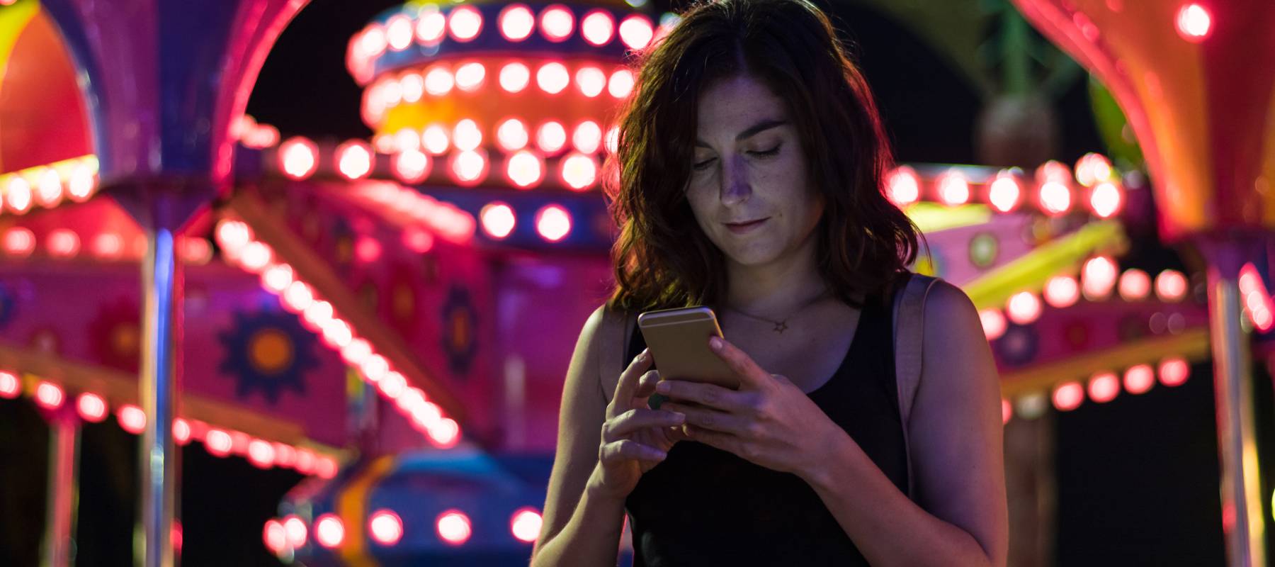 A woman looks at her smartphone while at a fair.