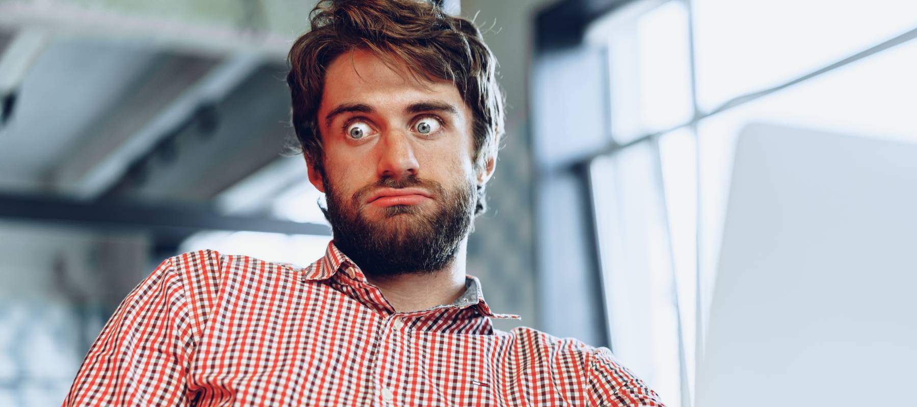Man with beard sitting in front of a laptop looking perplexed