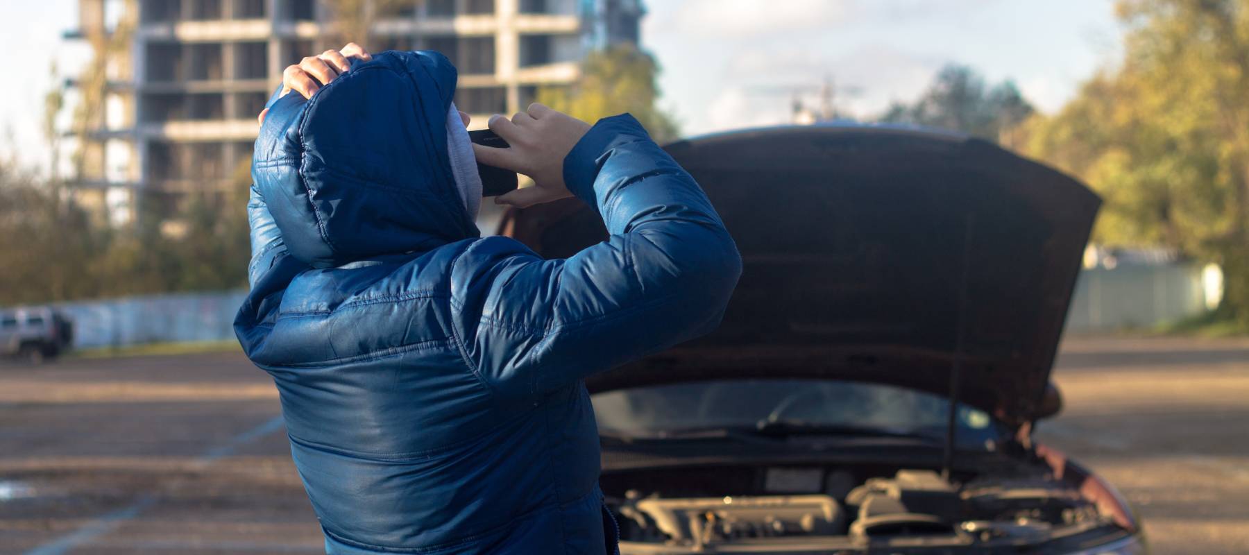 Man calling someone with car's hood up
