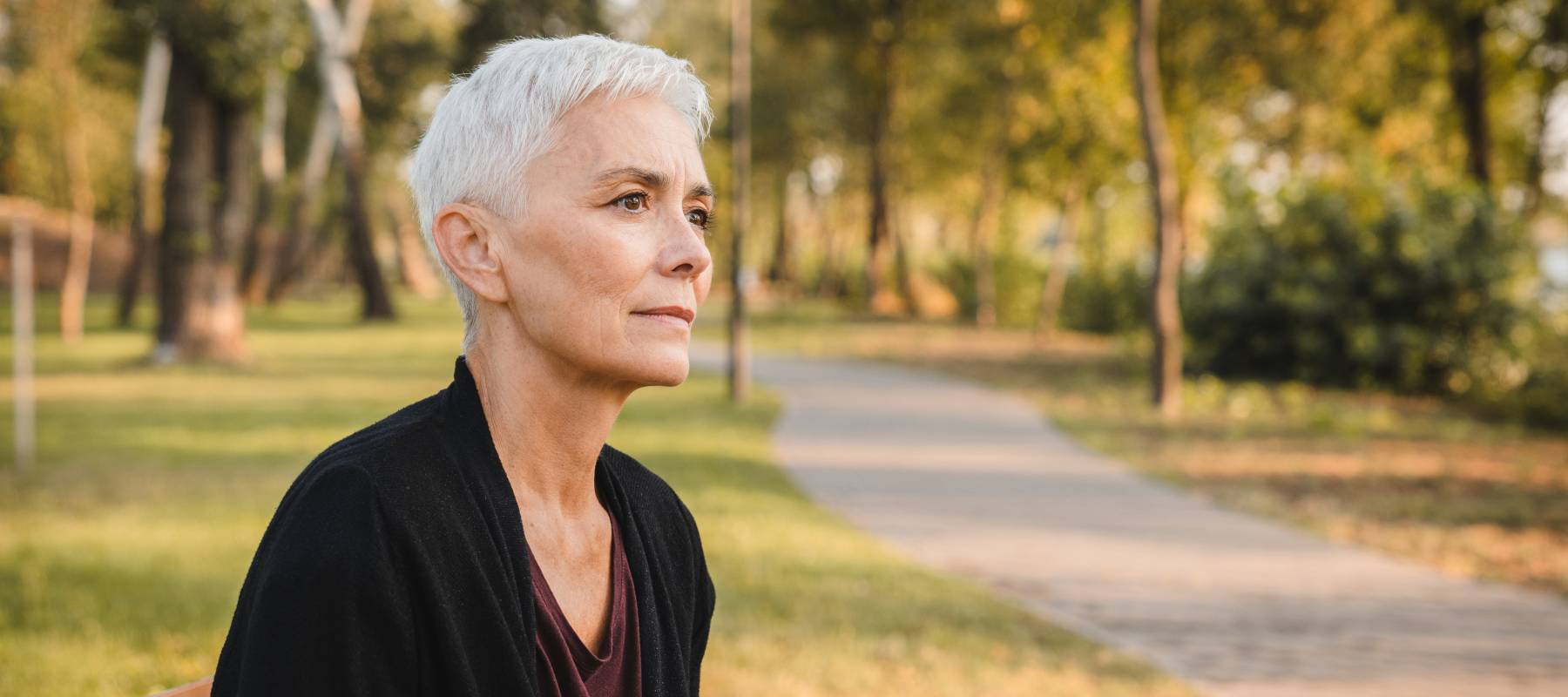 Contemplative Elderly Woman Relaxing on a Park Bench in Autumn