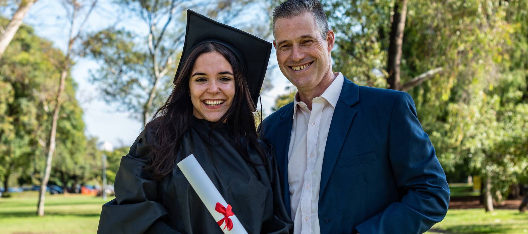 Happy caucasian graduated girl with her father on her graduation day. They are both looking at camera
