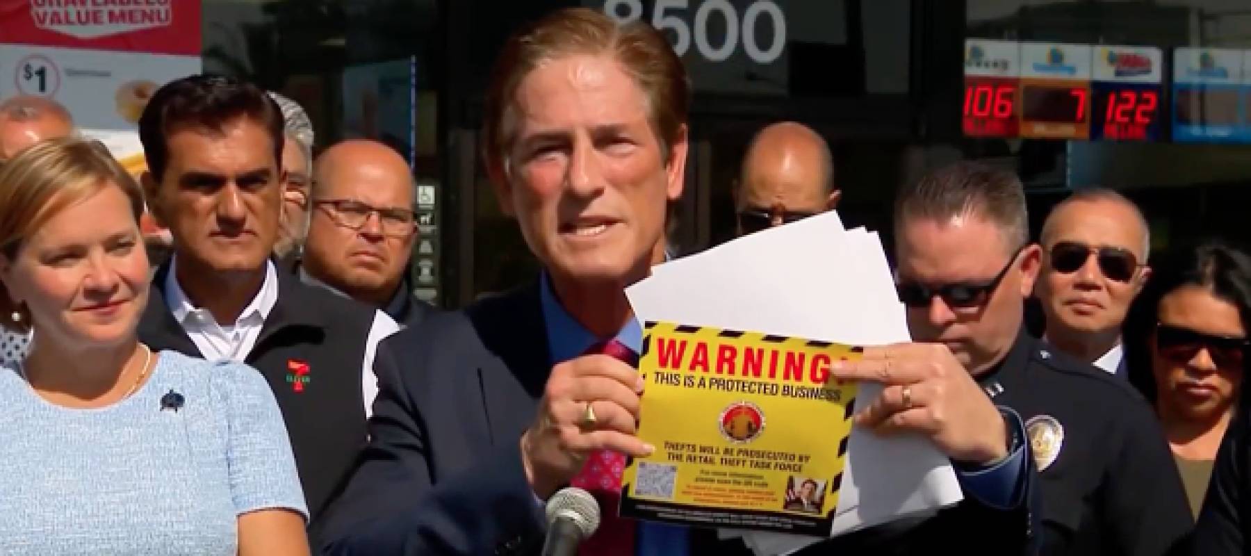 Man holds window sticker decal in front of store.