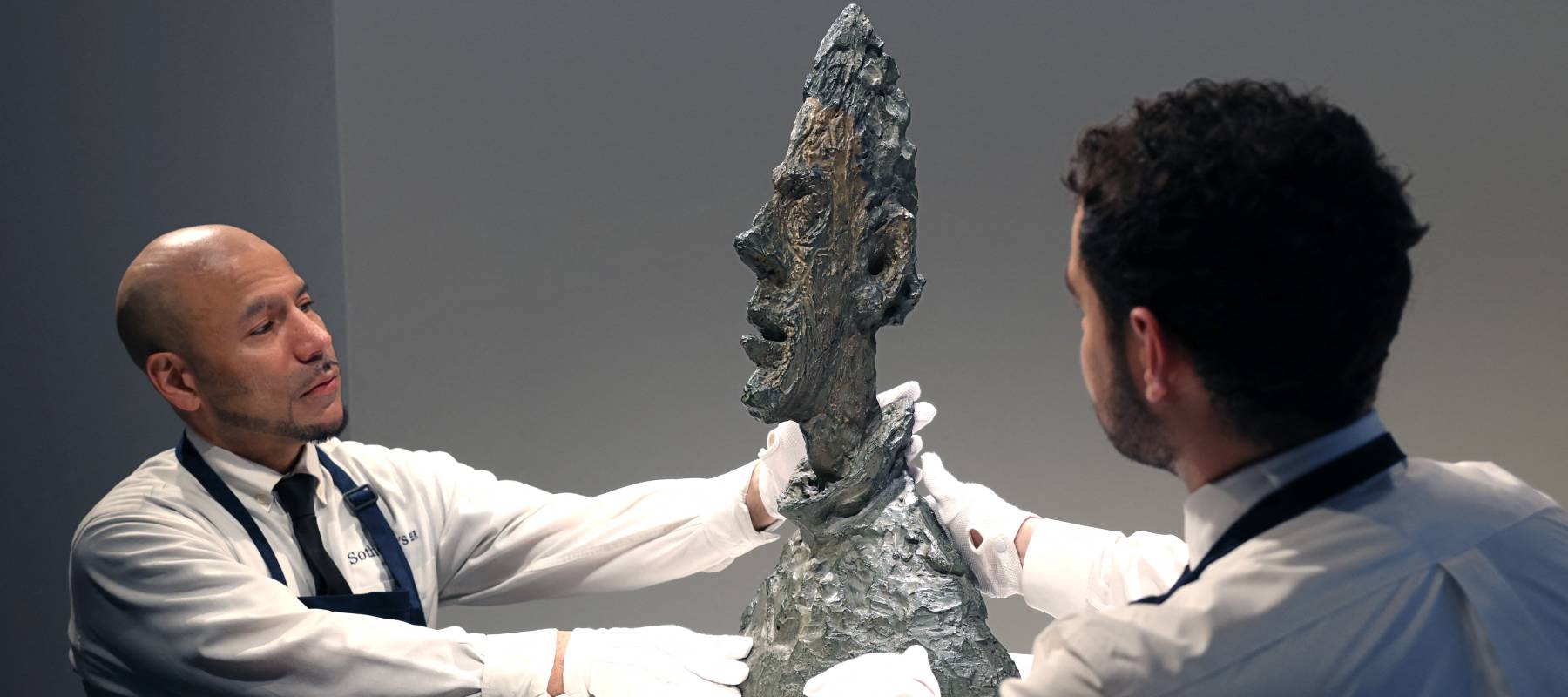 Two men place a sculpture on a table.