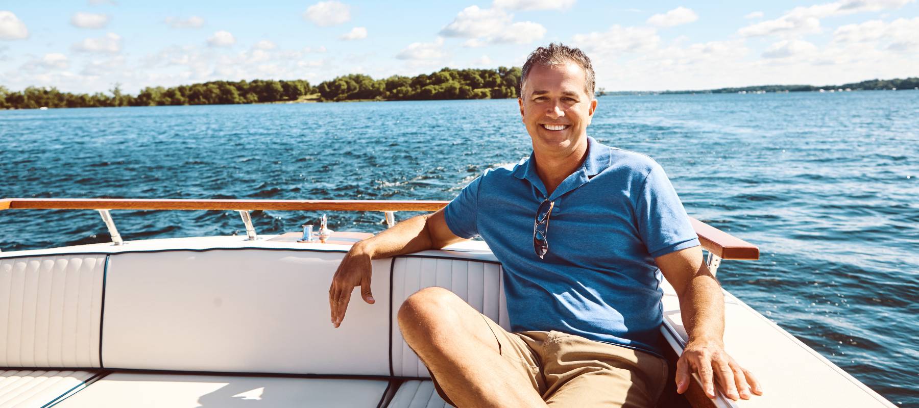Wealthy man sitting on boat on lake.