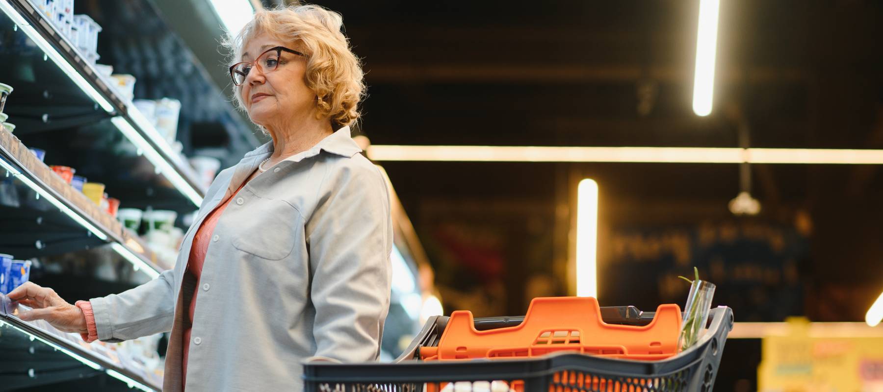 An older woman grocery shopping.