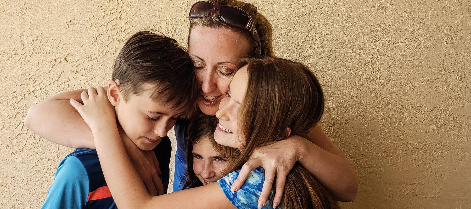 A woman hugs three children.