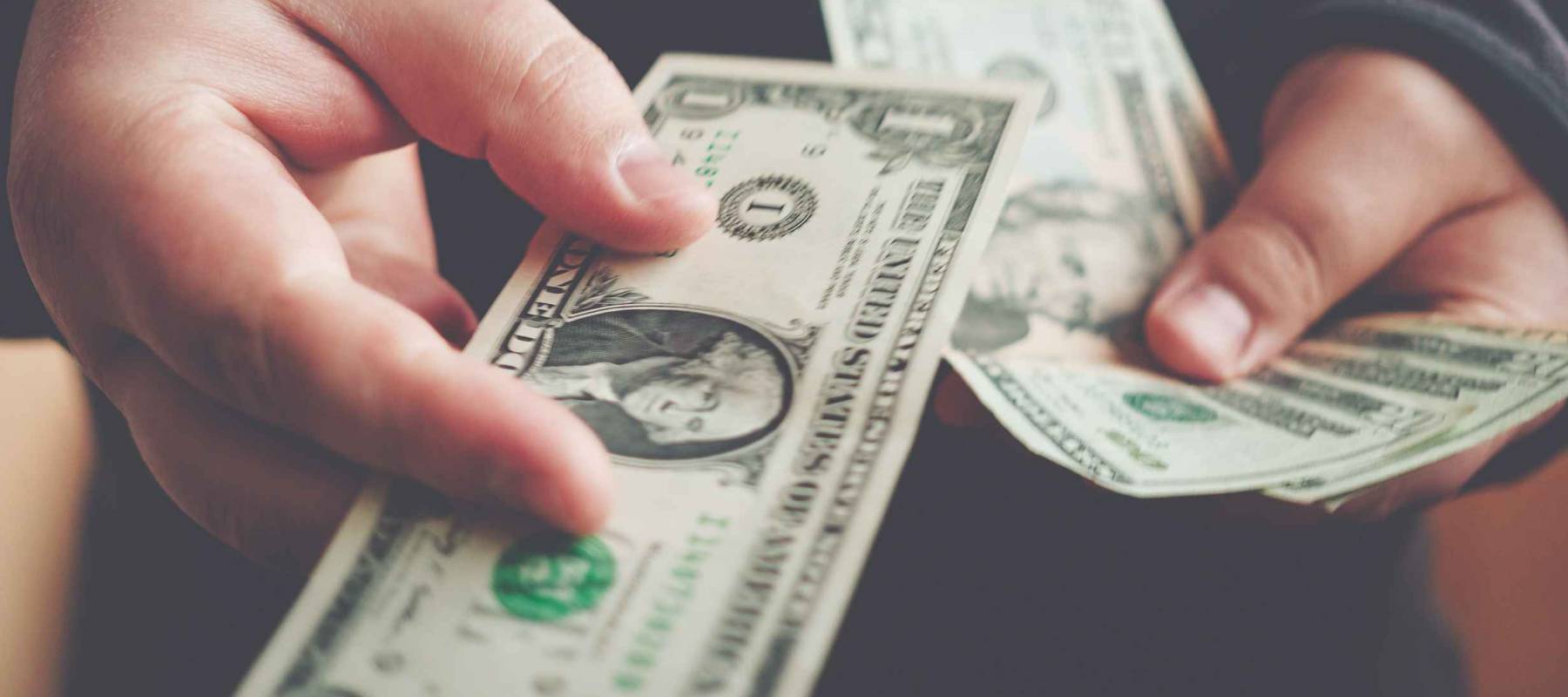 Man giving one us dollar banknote and holding cash in hands. Money credit concept. Toned picture.