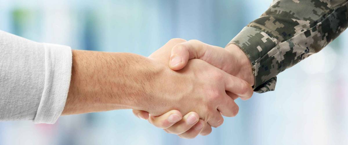 Soldier and civilian shaking hands on blurred background