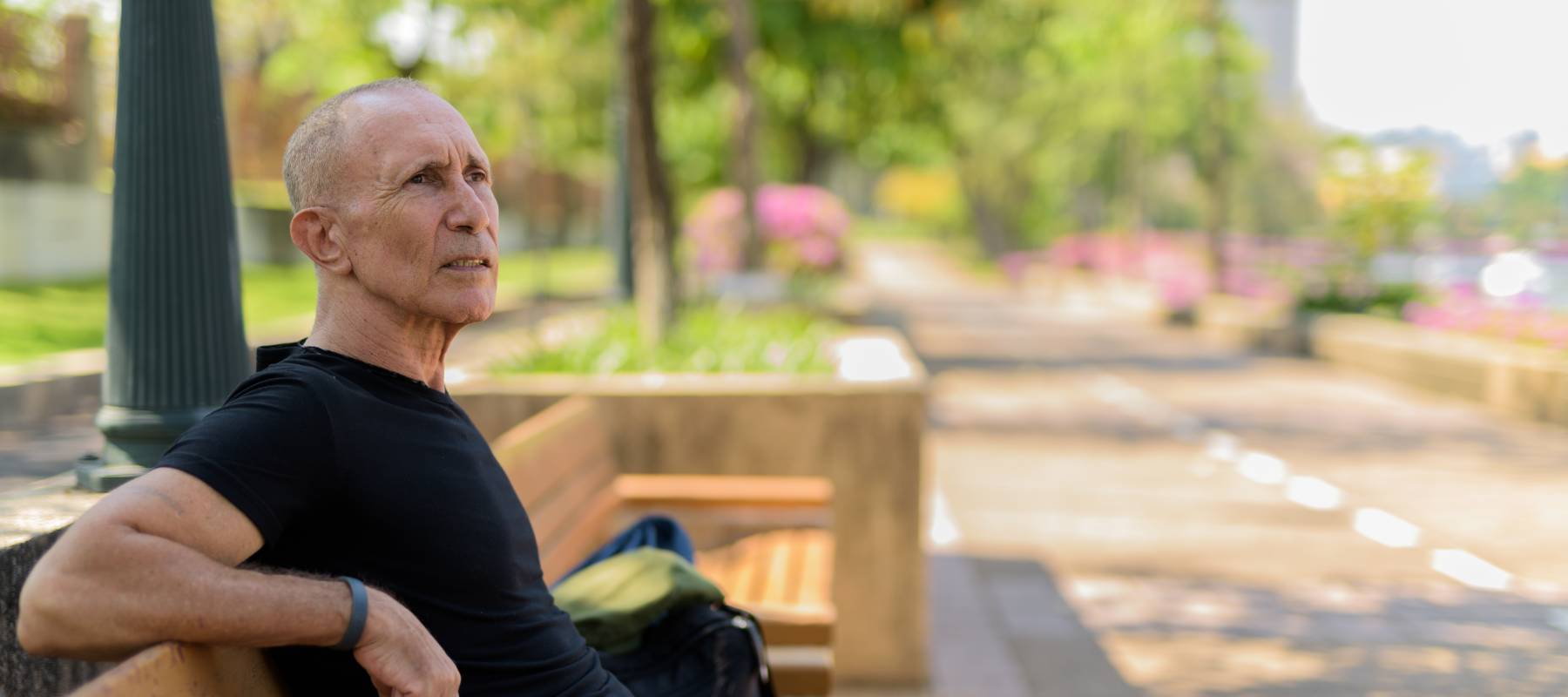 Older tourist man thinking while sitting on the wooden bench.