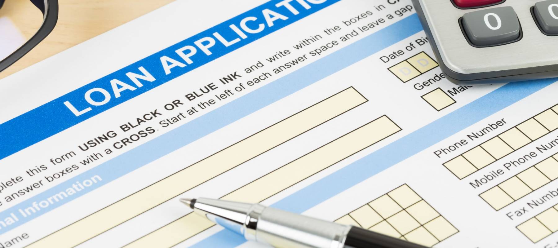 Loan application form with calculator, glasses, and pen