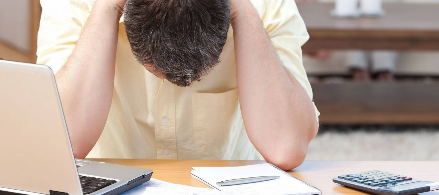 Man calculating his bills while his family are on the sofa