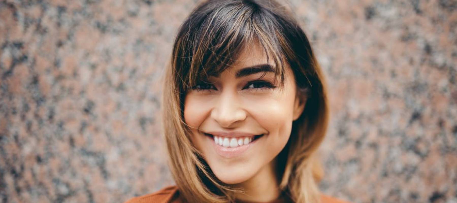 Young woman in orange sweater smiling