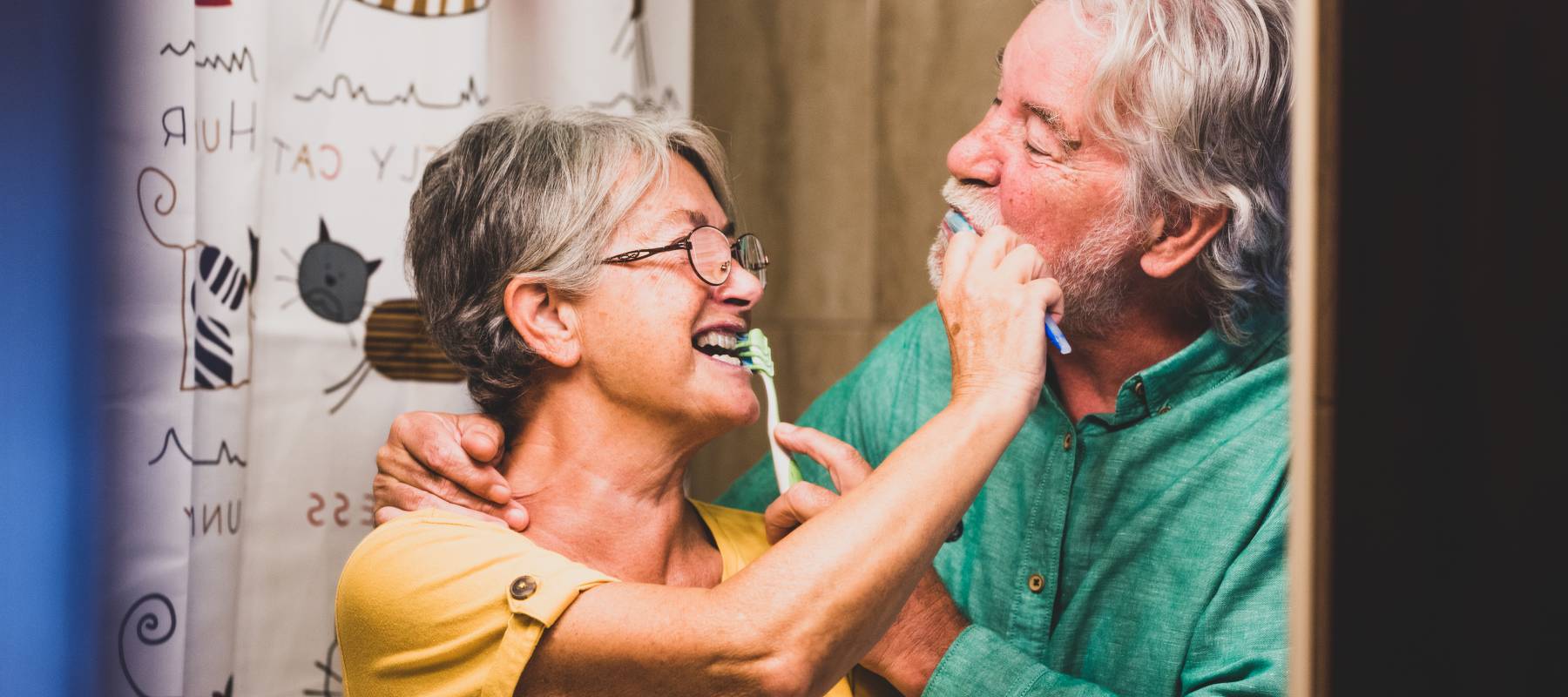 Elderly couple brushing each other's teeth.