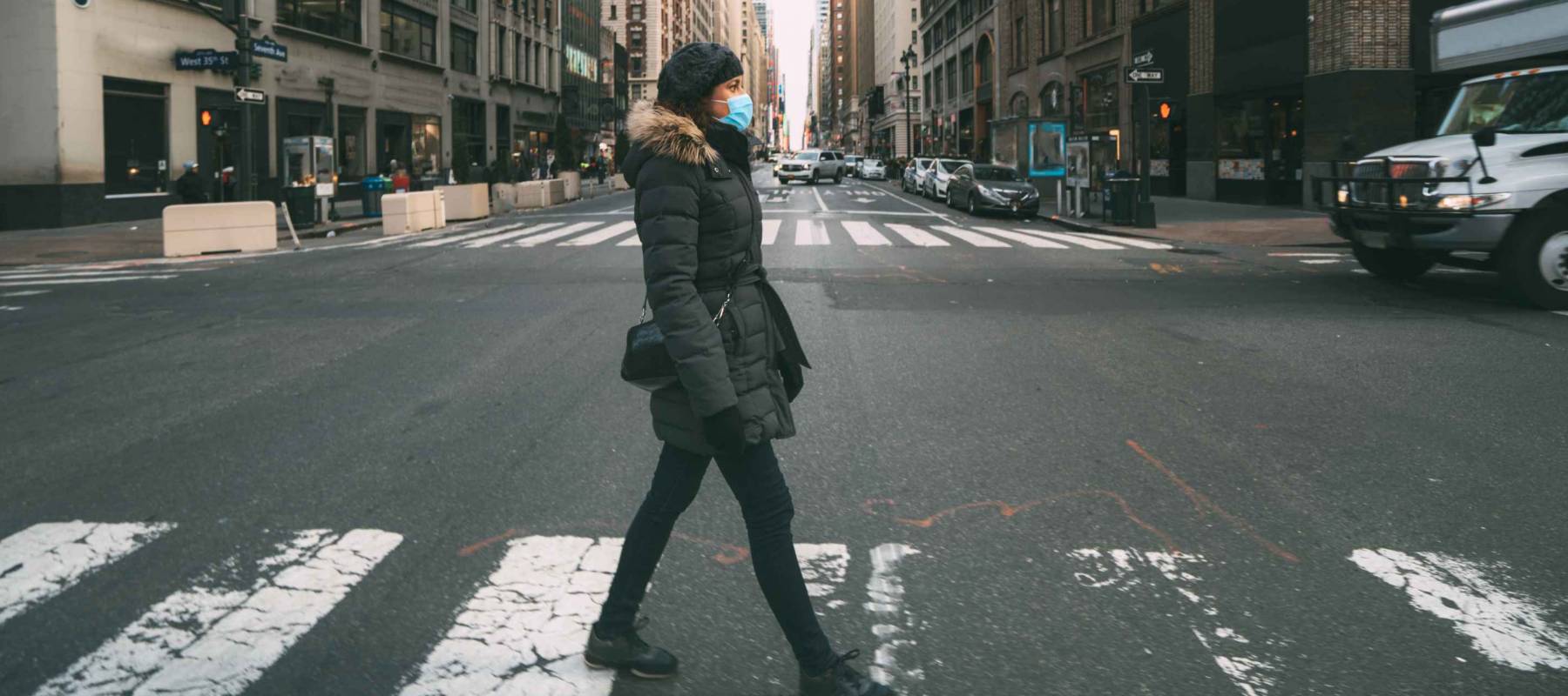 Woman wearing surgical mask going through crosswalk in midtown manhattan.Concept of Coronavirus, COVID-19 and quarantine