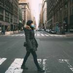 Woman wearing surgical mask going through crosswalk in midtown manhattan.Concept of Coronavirus, COVID-19 and quarantine