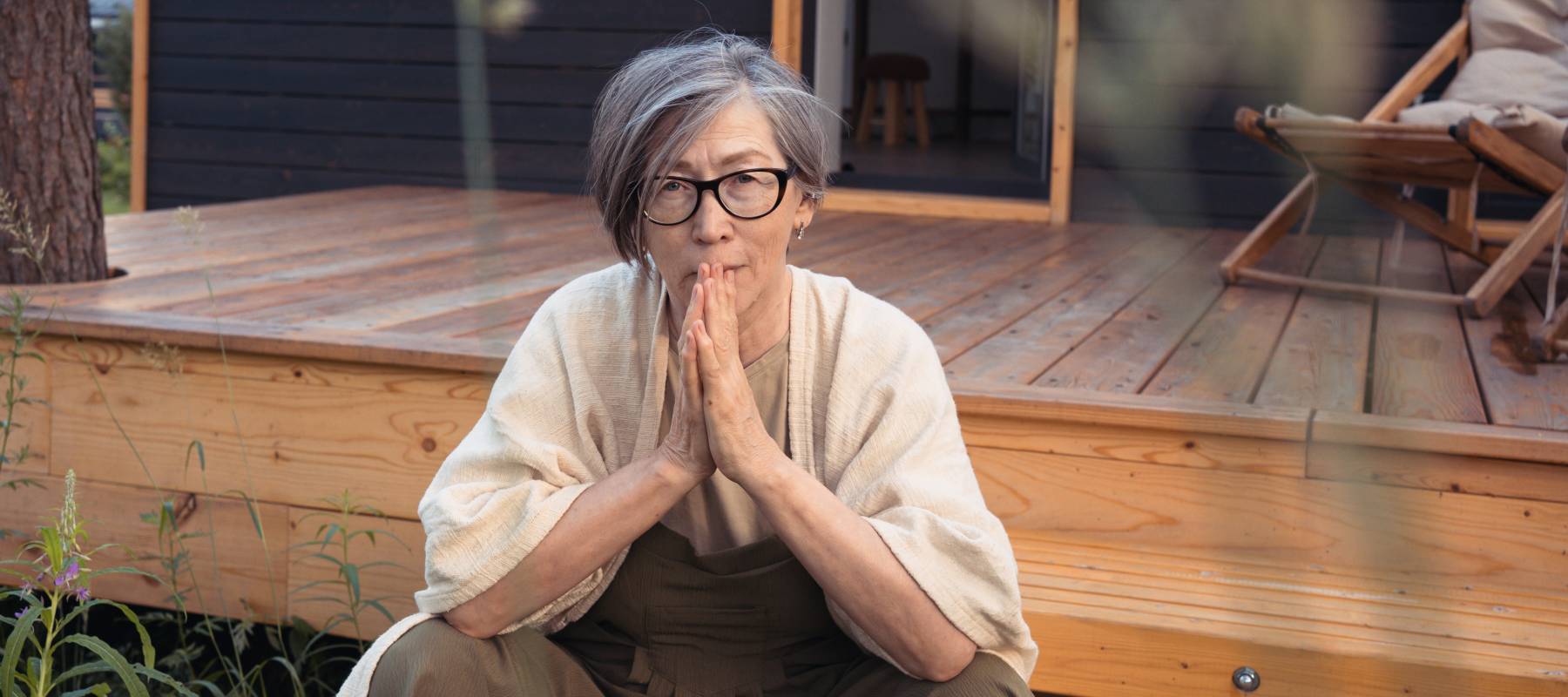 Woman sitting outside on a porch, thinking.