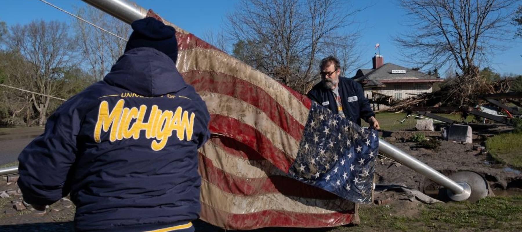 Residents rescue a US flag on May 21, 2020, after its flag pole was brought down by flood waters in Sanford, Michigan.
