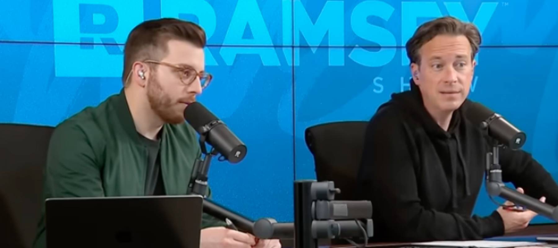 Two men speaking on mics, on camera.