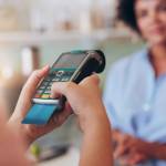 Young woman paying by credit card at juice bar. Focus on woman hands entering security pin in credit card reader.