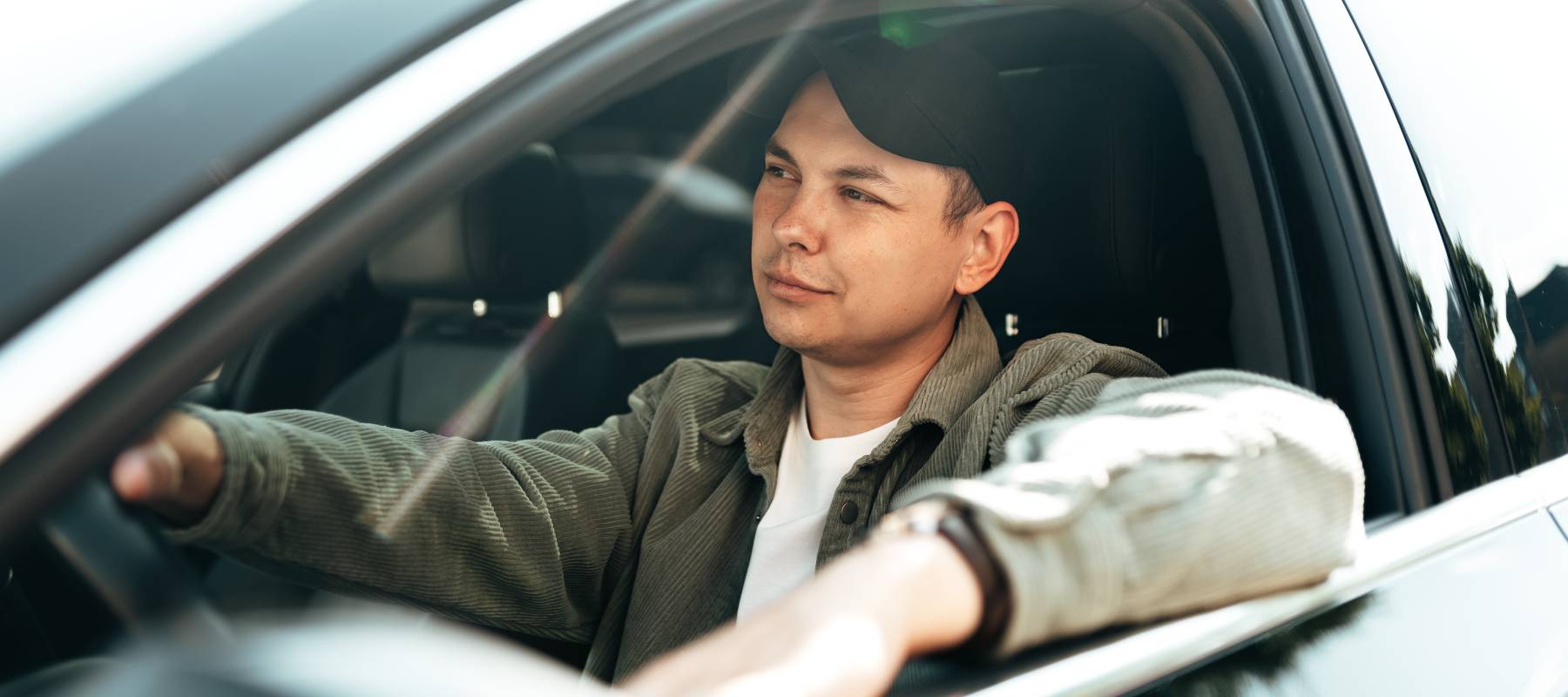 Young smiling man sitting in a car with open window