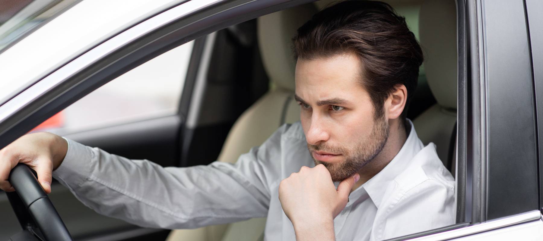 Contemplative young  professional man driving car.