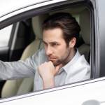 Contemplative young  professional man driving car.