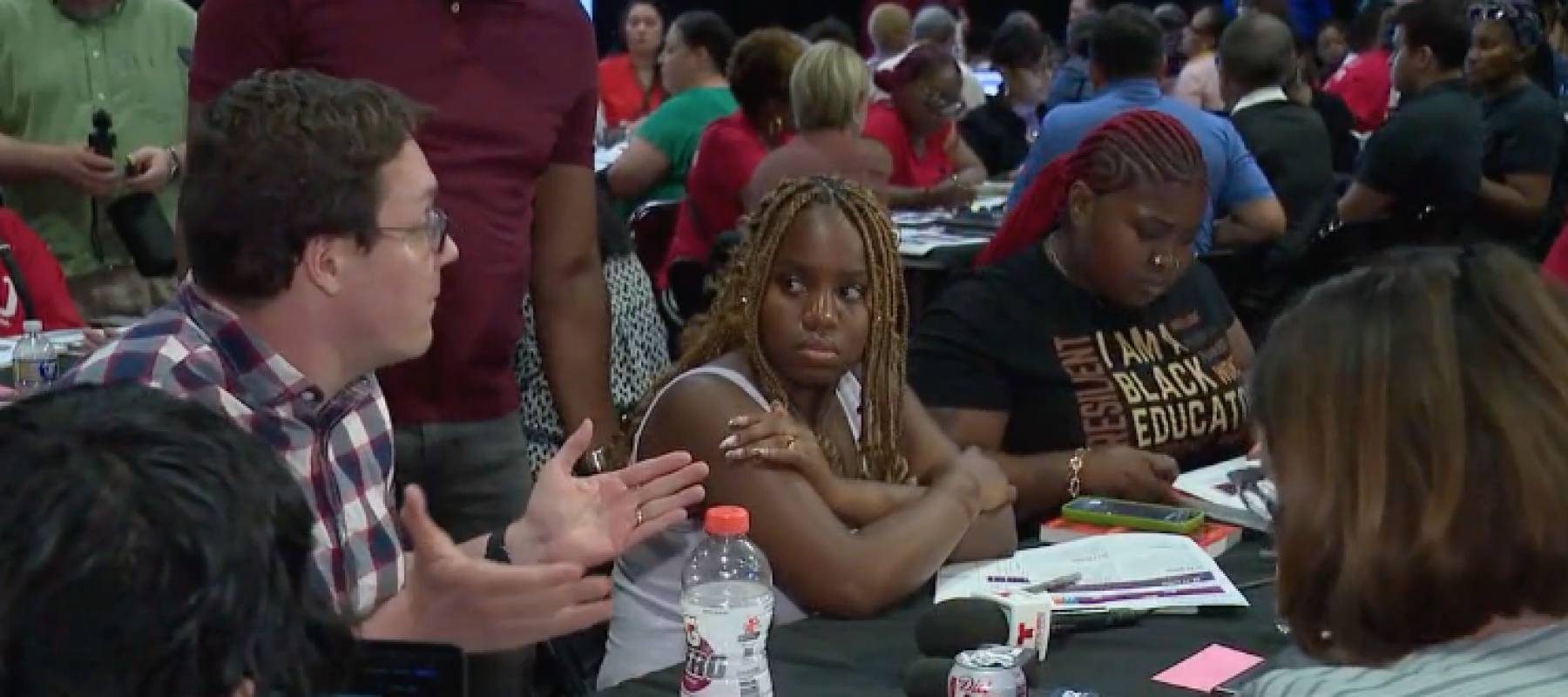 Man speaking with others seated at a meeting table.