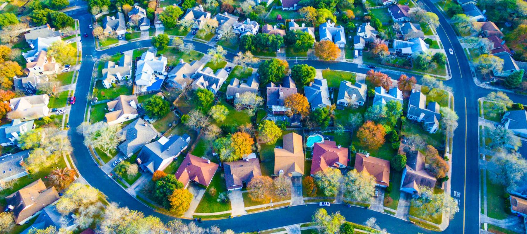 Aerial View Over Modern Suburb Home Community neighborhood with colorful Fall Autumn trees around curved streets and new development outside of Austin , Texas