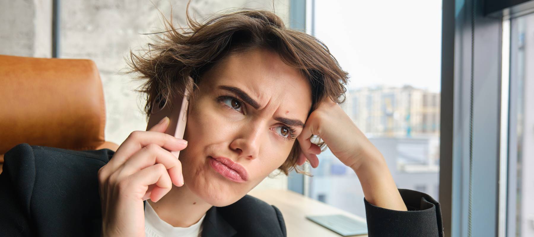 Woman scrunching her face while on the phone.