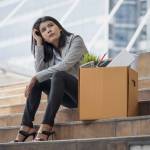 Unemployed stressed office people sitting outside office with her box of office properties. She was dismissed from business downsizing. Failure and layoff concept