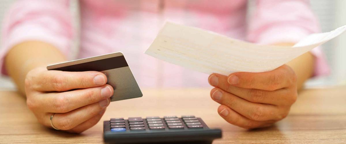 woman is holding bill and credit card in hands  and calculating the costs