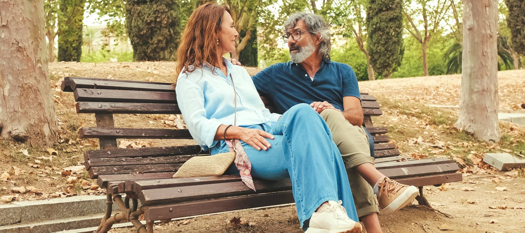 Couple talk while seated on a park bench.