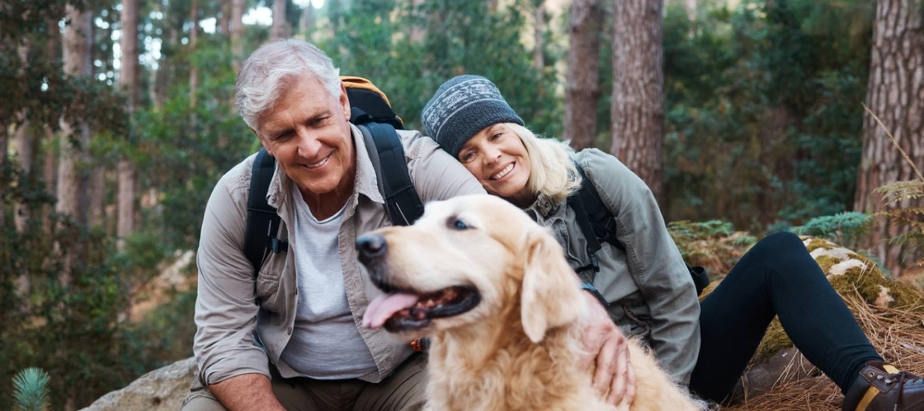 senior couple with their dog in the woods for a wellness walk