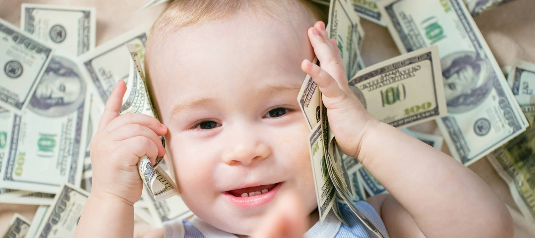 Cute happy baby playing with a lot of money, American hundred dollars cash