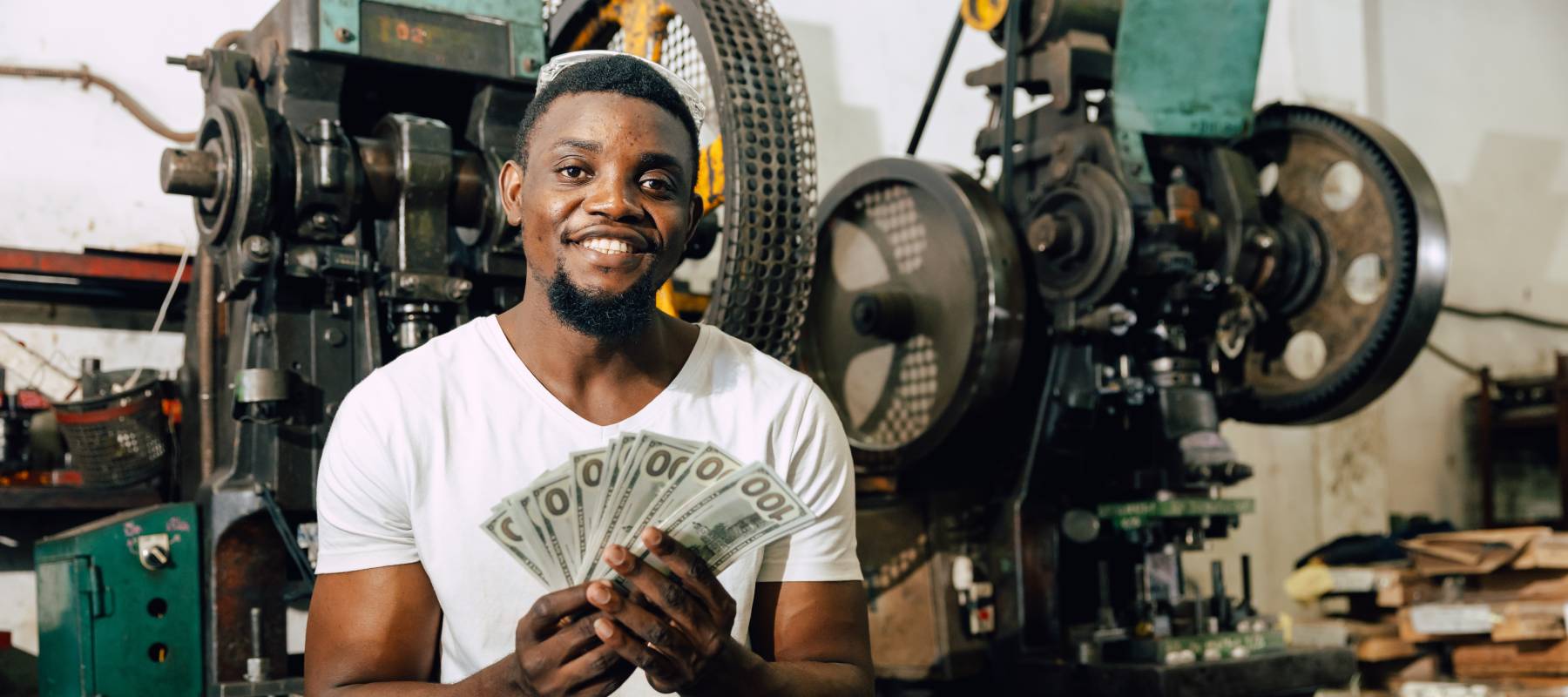 Black  man enjoys money from hard work in factory