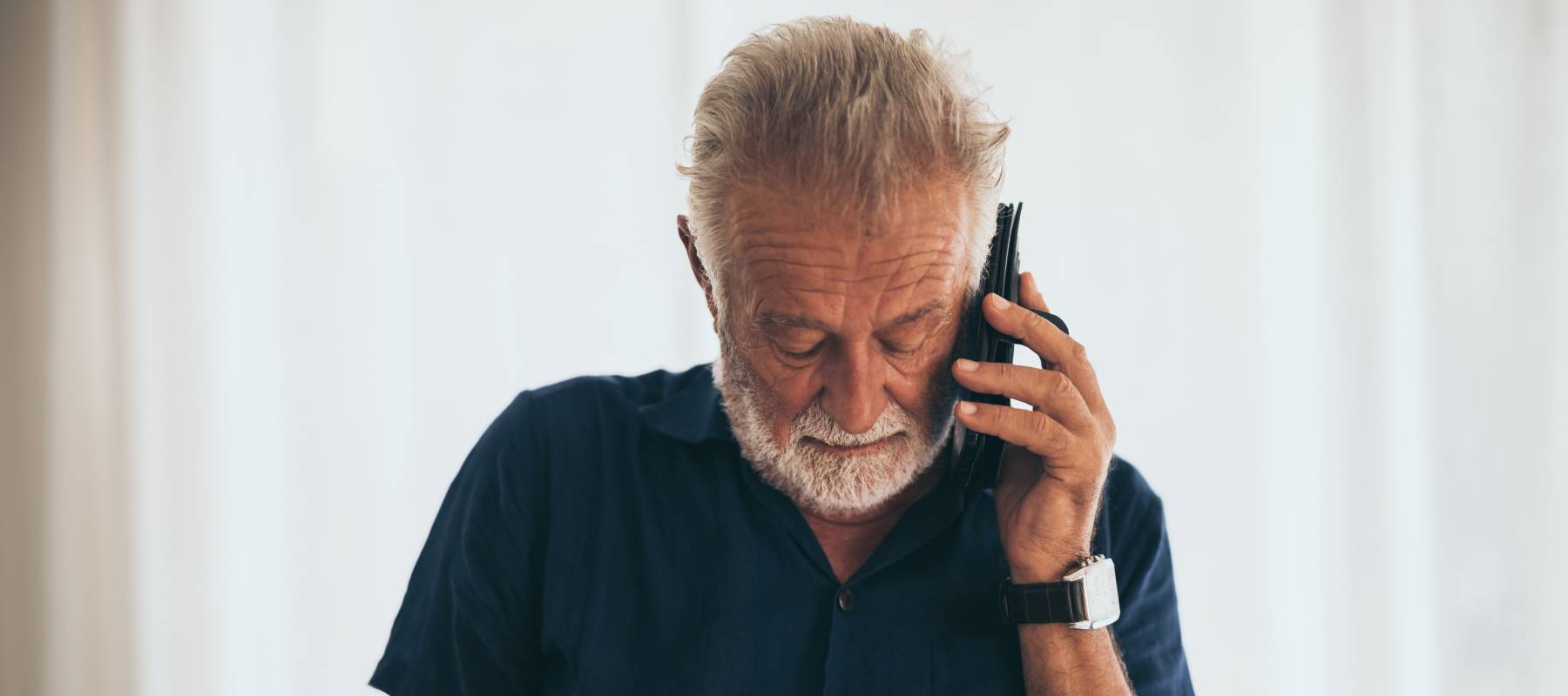 Middle-aged businessman talking on mobile phone at home.