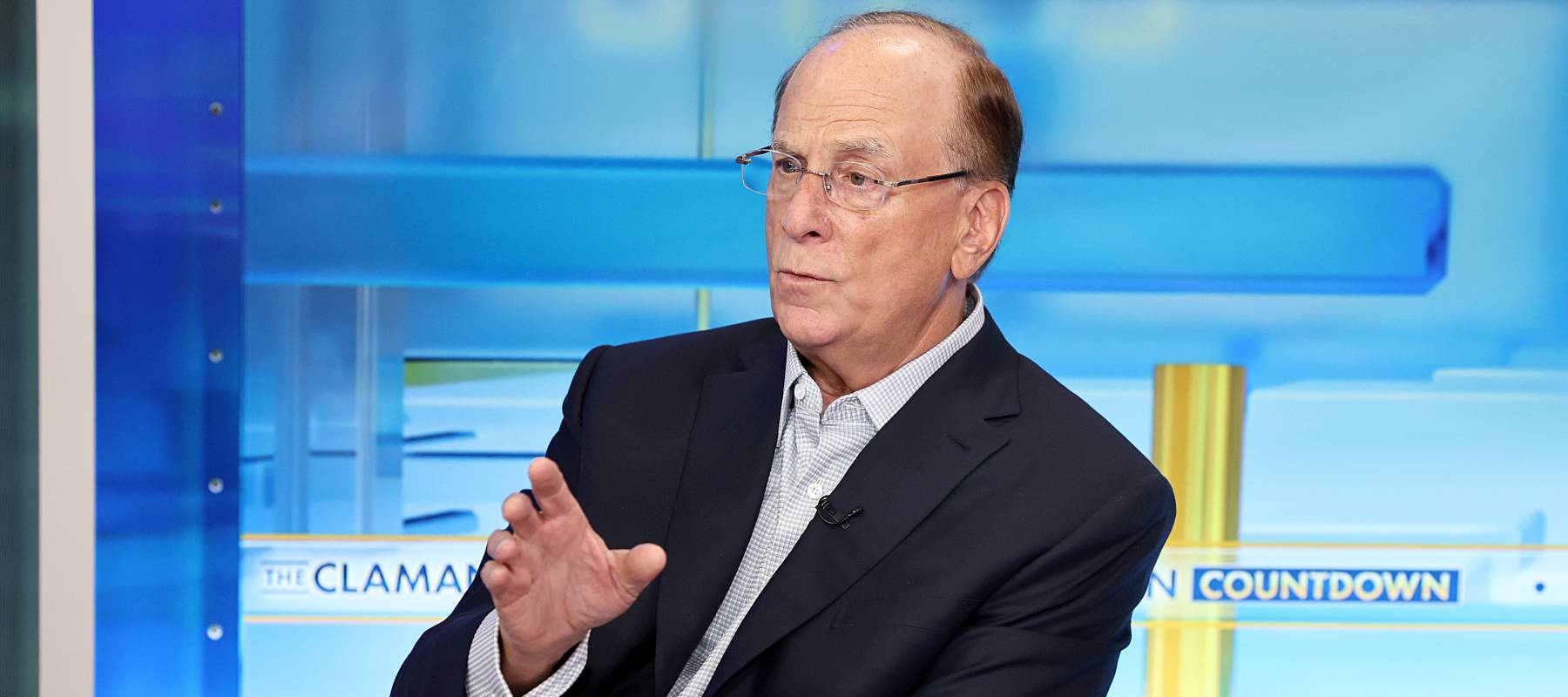 BlackRock CEO Larry Fink peers over his glasses with one eyebrow furrowed and holds up a single hand as if to forestall questions.
