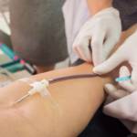 Pretty, young woman giving blood/plasma. Laying down while the procedure takes place (color toned image; shallow DOF)