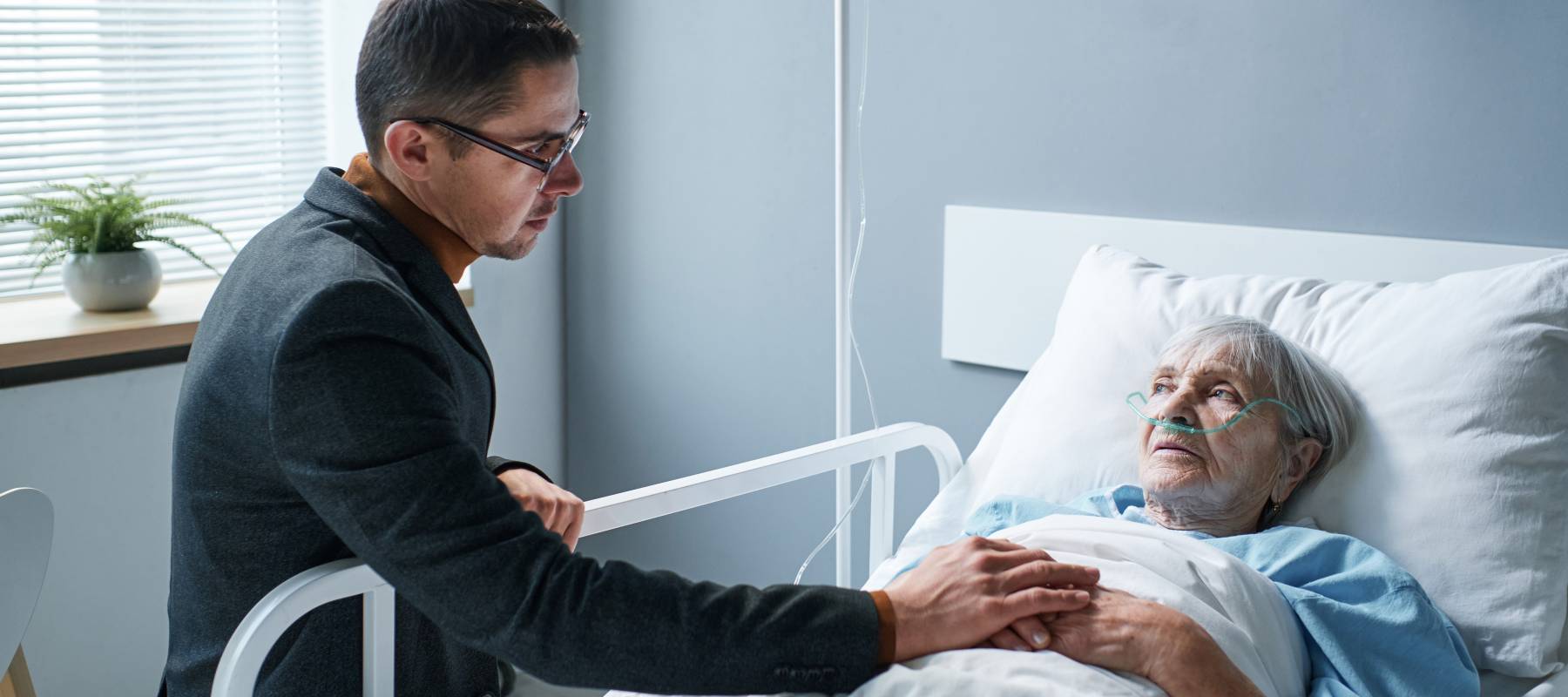 Son visits elderly woman in hospital.