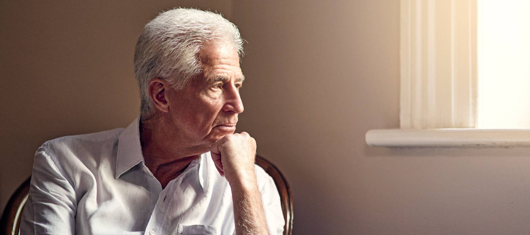 Worried looking older man looking off to the side out the window.