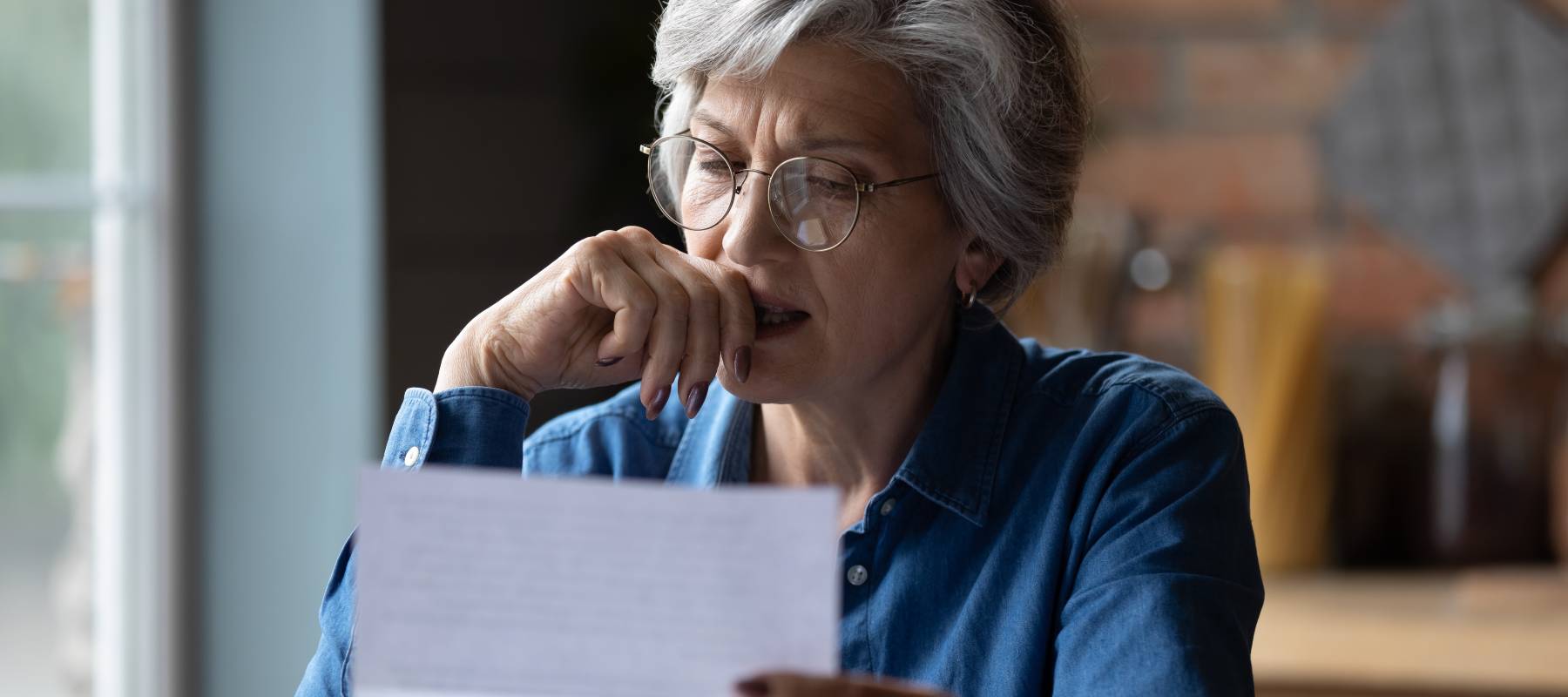 Woman receiving distressing news in a letter.