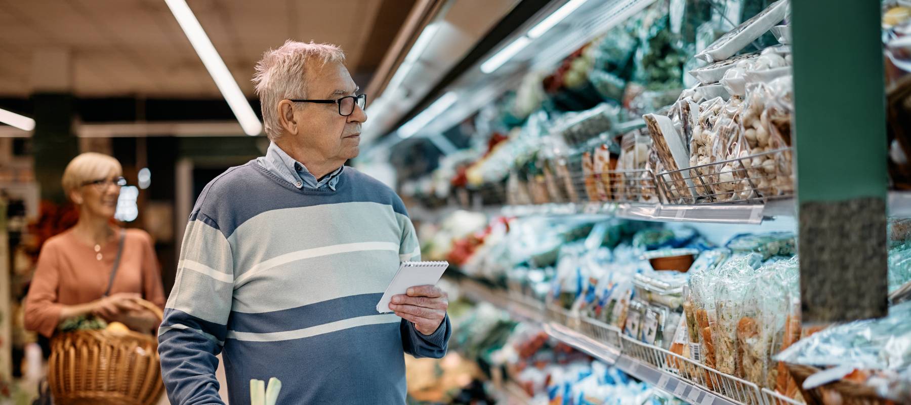 An older man carefully follows his grocery list.