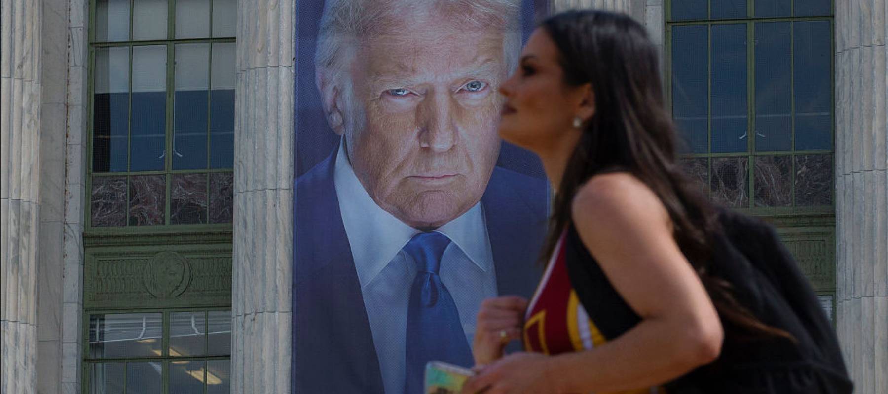 Woman walking past Trump banner.