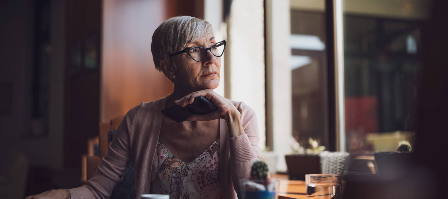 Mature woman in cafe looking pensively out the window.