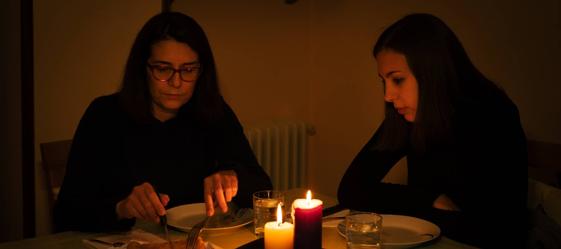 One-parent family dining by candlelight. Blackout concept.