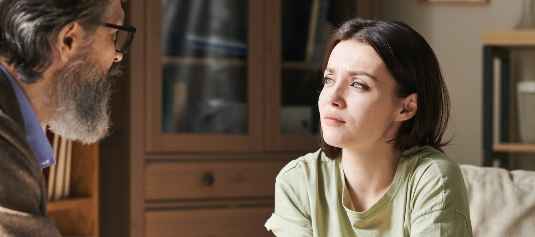 A young unhappy woman in front of an older man.