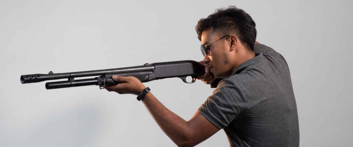 Young man pointing shotgun to the side